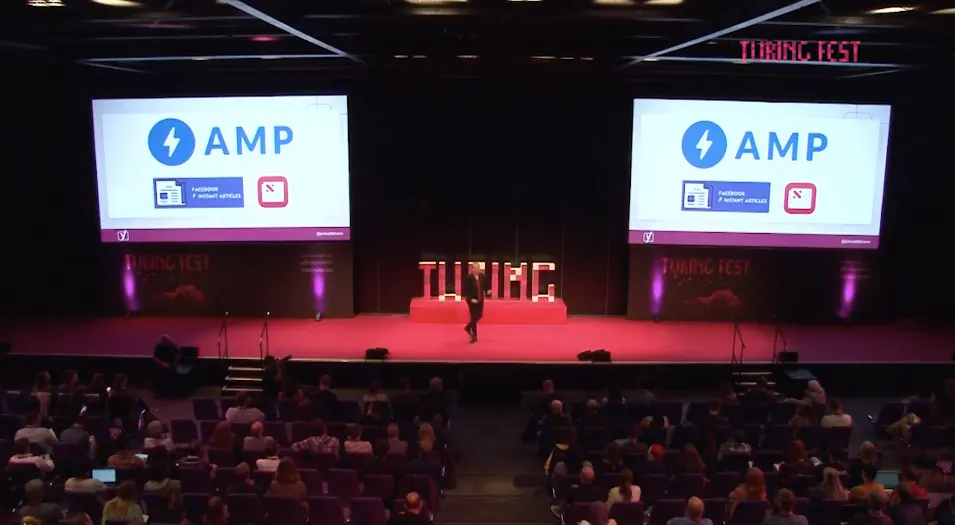 Wide Turing Fest stage; twin screens show AMP, Facebook Instant Articles and Apple News logos